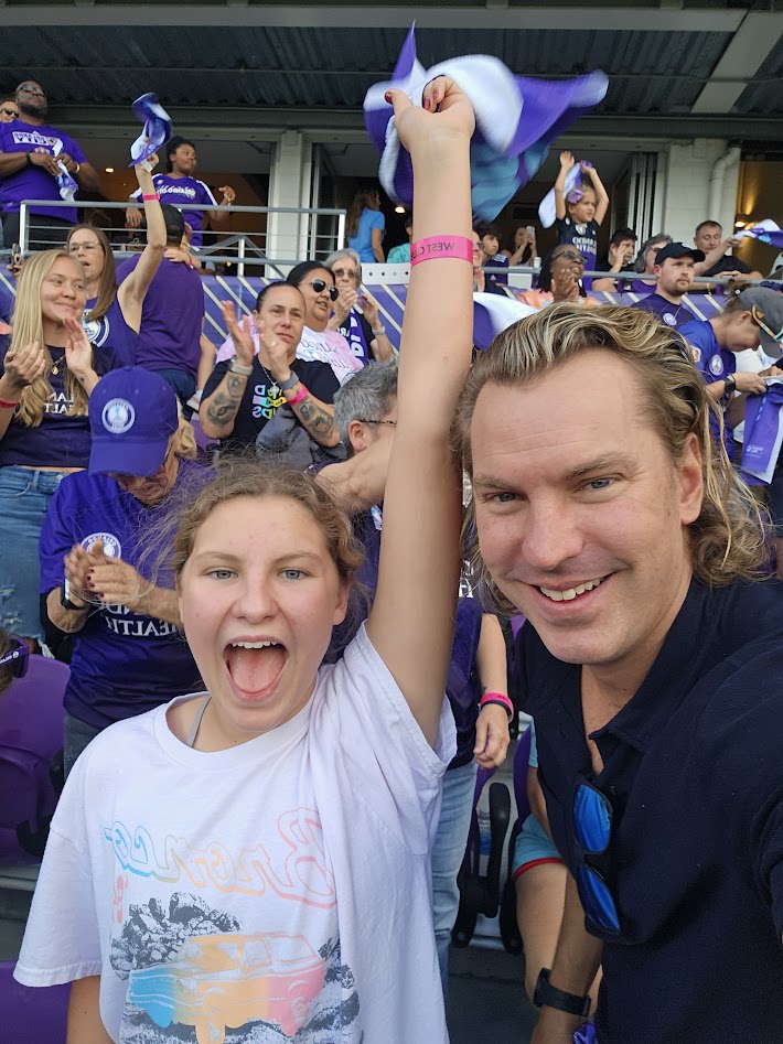 Rob and his daughter celebrating in the stands at an Orlando Pride match